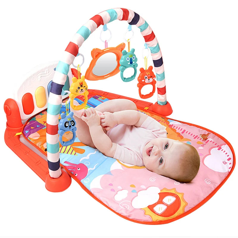 Baby lying on a colorful play mat with a striped arch, holding feet. Hanging toys and a small mirror are attached overhead. The mat has playful animal graphics.