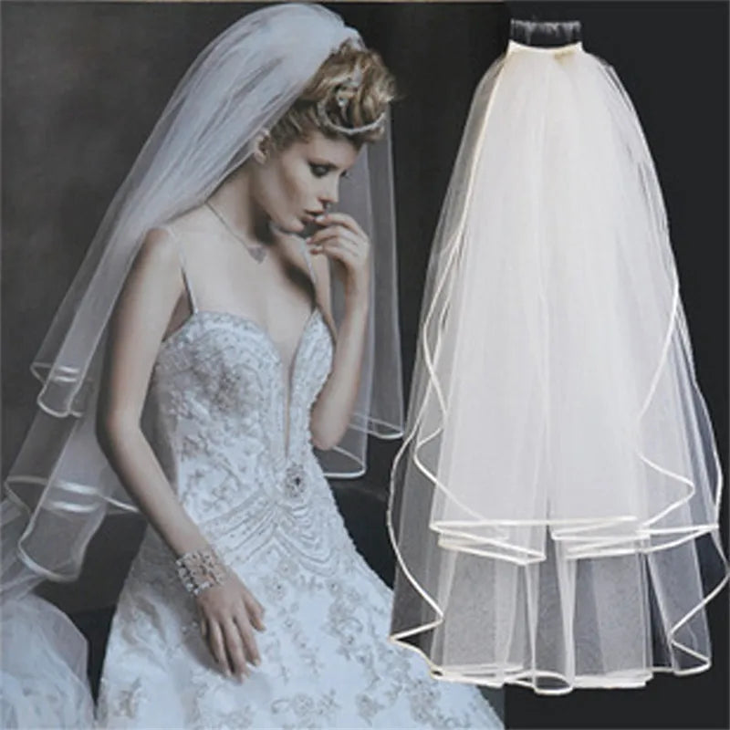 Bride in a detailed lace wedding dress and veil, with focus on her elegant pose and the multi-layered, sheer ivory veil with delicate trim displayed alongside.