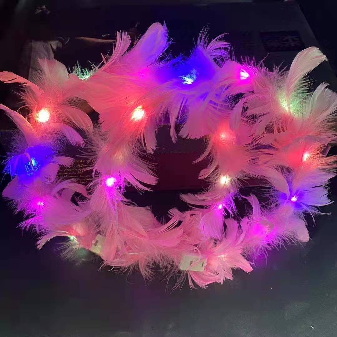 A fluffy wreath of pink feathers adorned with glowing multicolored LED lights in shades of pink, purple, and white, set against a dark background.