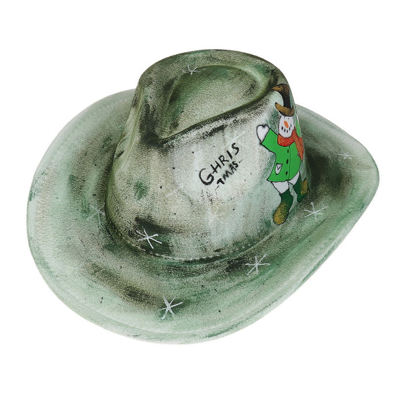 Green cowboy hat with a snowman illustration, red scarf, text "CHRISTMAS," and snowflakes. The hat has a weathered look, combining festive and rustic elements.
