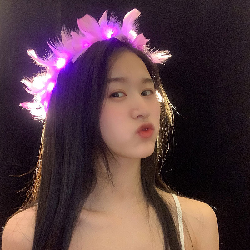 Young woman with long dark hair wearing a glowing pink feather headband, making a playful pout against a dark background.