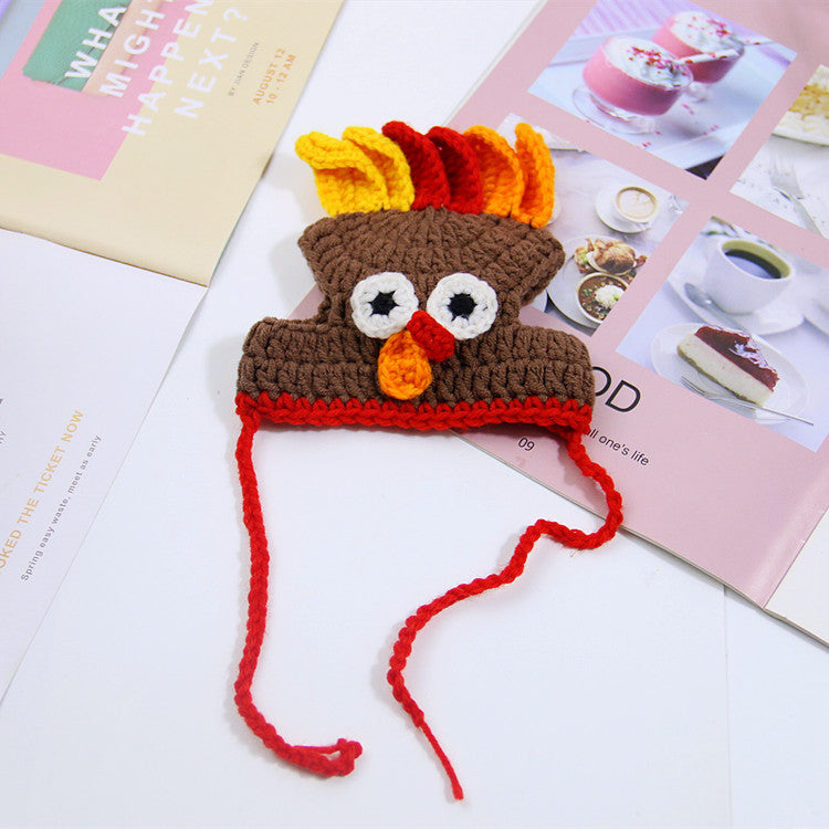 Crocheted turkey hat with colorful feathers, eyes, and beak, placed on open magazines highlighting desserts and text. Red ties hang from the hat.