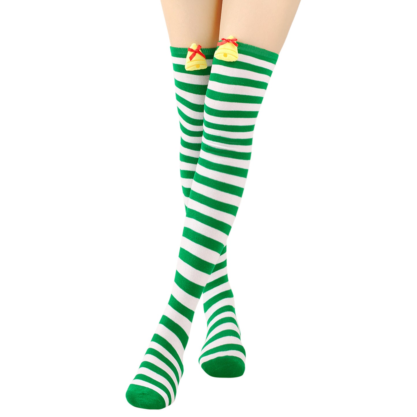 Knee-high socks with green and white stripes, featuring decorative yellow bells with red bows near the top, worn by a person standing with feet crossed.