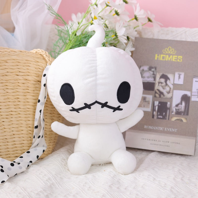 A plush toy with a round white body and big black eyes sits on a textured surface. In the background, there's a wicker basket and decorative elements like flowers and a magazine.