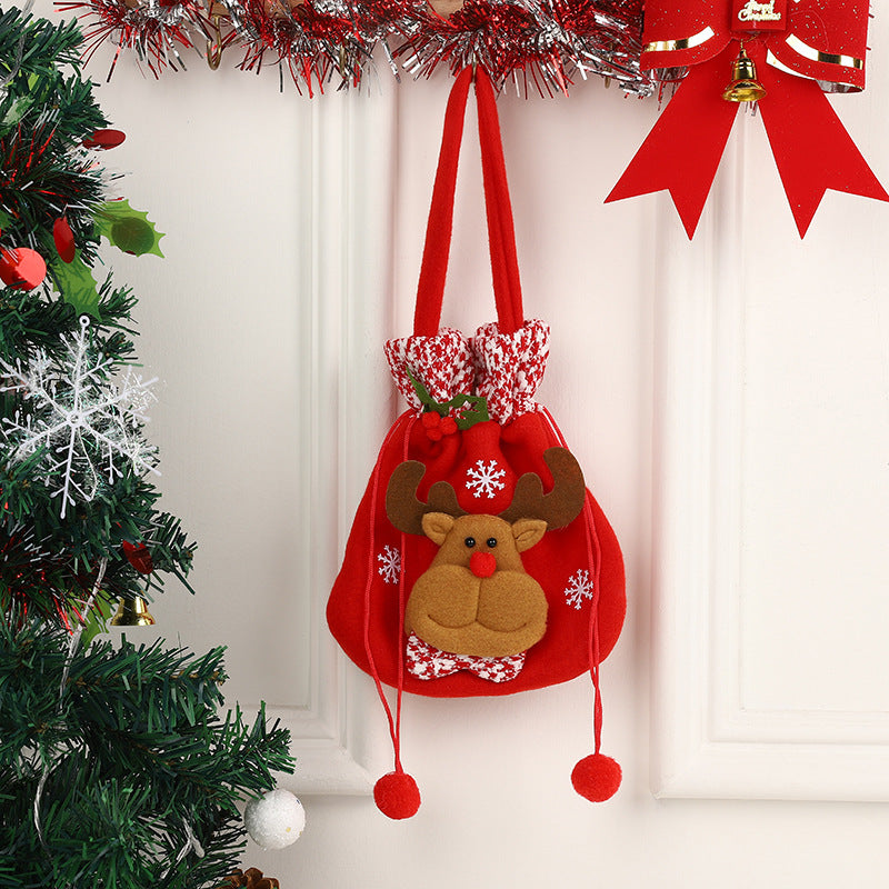 Red Christmas bag with a reindeer design hangs on a white wall, surrounded by festive greenery, tinsel, and a red bow with a golden bell, evoking holiday cheer.