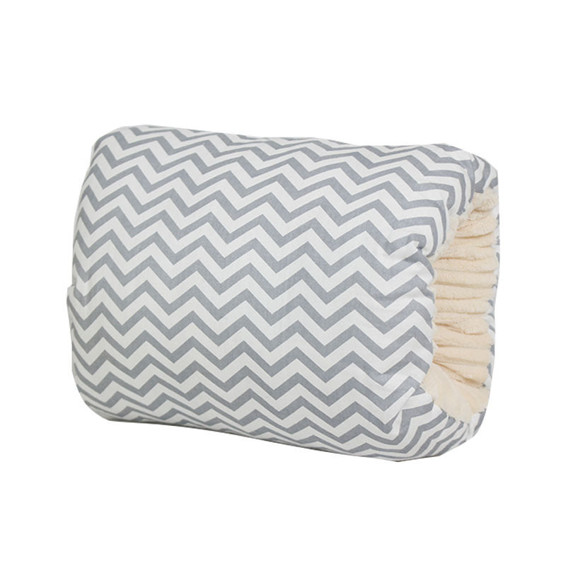 A cozy cylindrical pillow with a gray and white chevron pattern on the outside and a soft, beige interior.