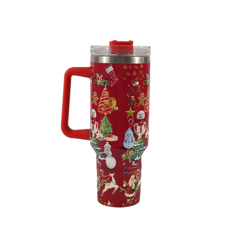 Red insulated tumbler with festive Christmas designs featuring snowmen, Christmas trees, ornaments, Santa, and reindeer. Clear lid and red handle attached.