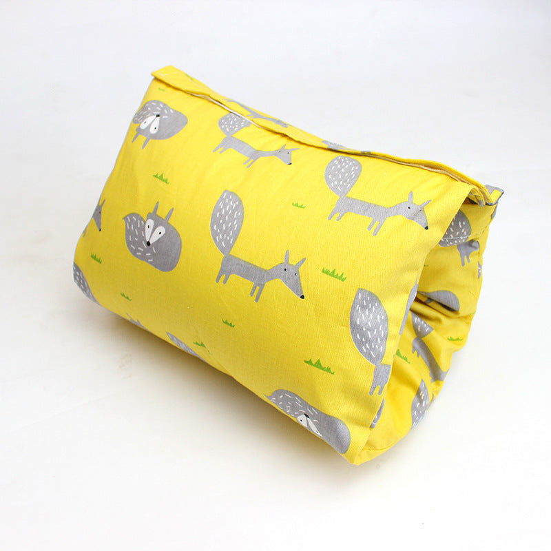 Yellow cushion cover with playful gray fox prints and small green grass patterns, set against a plain white background. The cover is slightly folded, emphasizing the fabric texture.