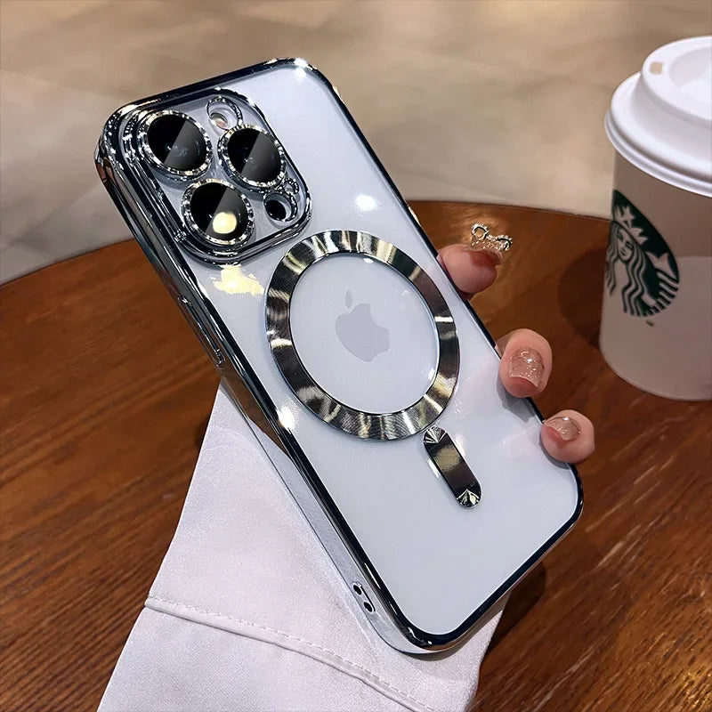 A hand holds an iPhone with a reflective chrome case featuring a circular design. A Starbucks cup sits on the wooden table in the background, creating a cozy atmosphere.