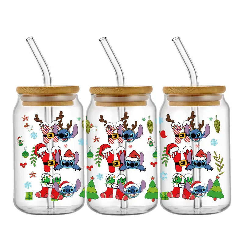 Three glass cups with bamboo lids and straws, decorated with festive images of a blue character in various holiday costumes, surrounded by Christmas trees and ornaments.