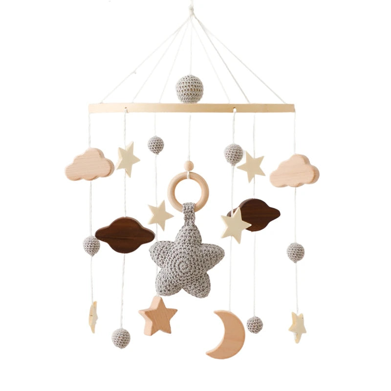 Handmade baby mobile featuring wooden stars, clouds, a crescent moon, and crocheted elements. Central crochet star with a wooden ring, suspended from strings.