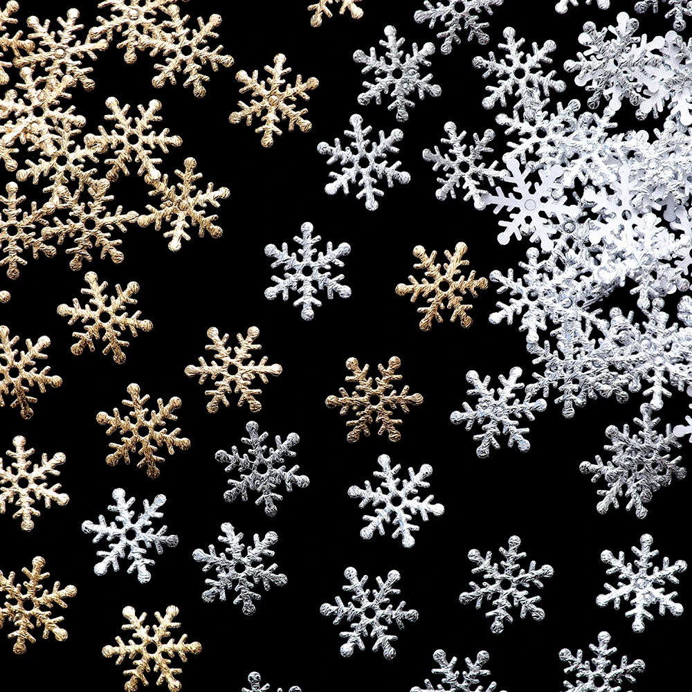 Gold and silver snowflake decorations scattered on a black background, creating a contrast of shimmering metallic colors.