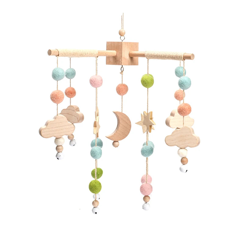 Wooden mobile with pastel felt balls, clouds, stars, and a crescent moon. It hangs from a horizontal bar, creating a calming and whimsical decoration.