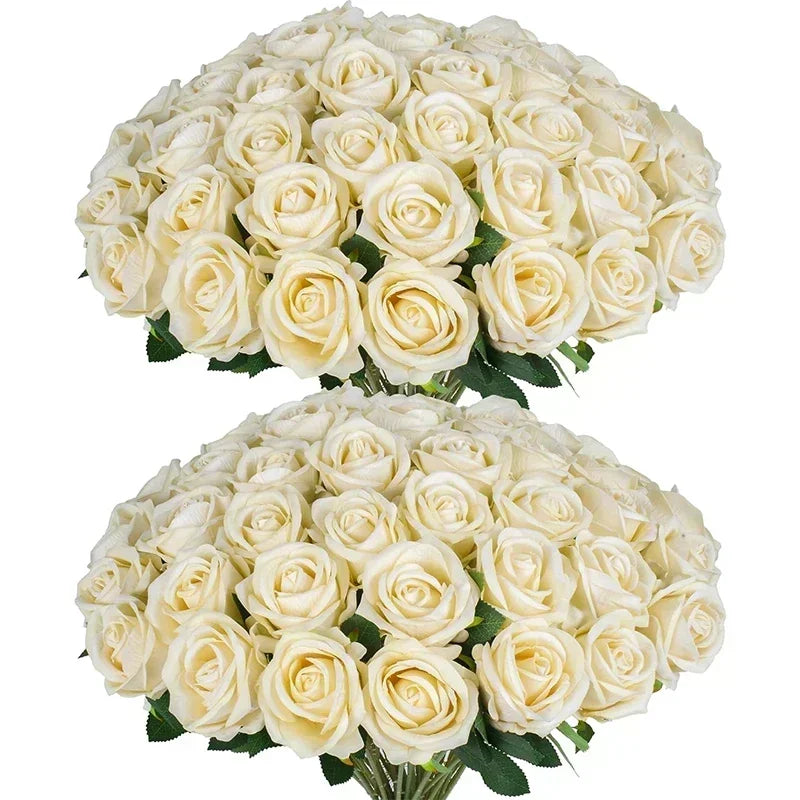 Two large bouquets of cream-colored roses with lush green leaves, tightly arranged and overlapping, filling the frame with their soft petals and elegant appearance.
