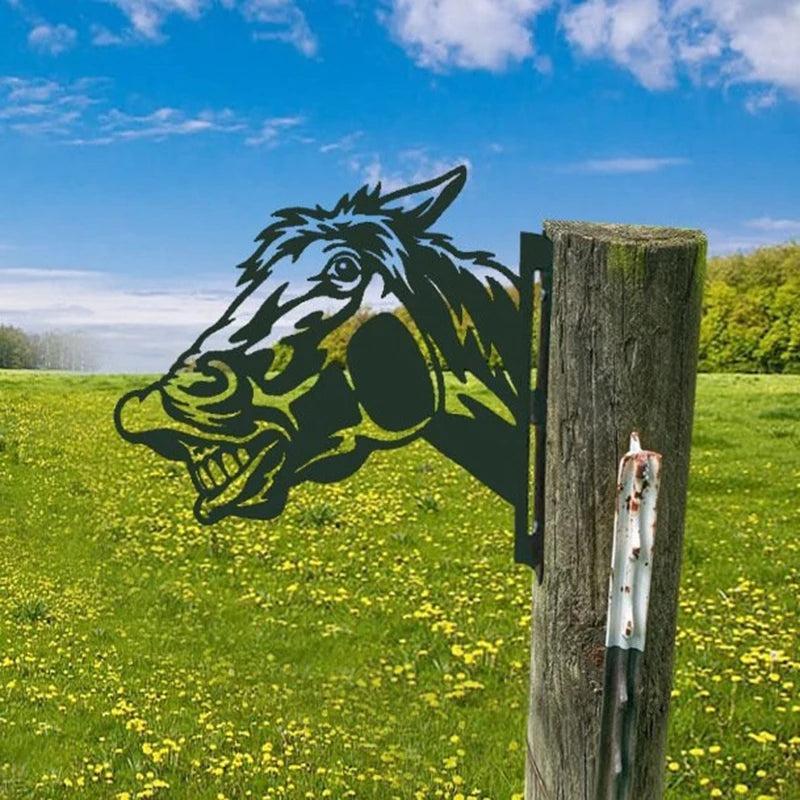 Metal horse silhouette fixed to a wooden post in a field with yellow flowers. Blue sky and trees in the background create a serene rural scene.