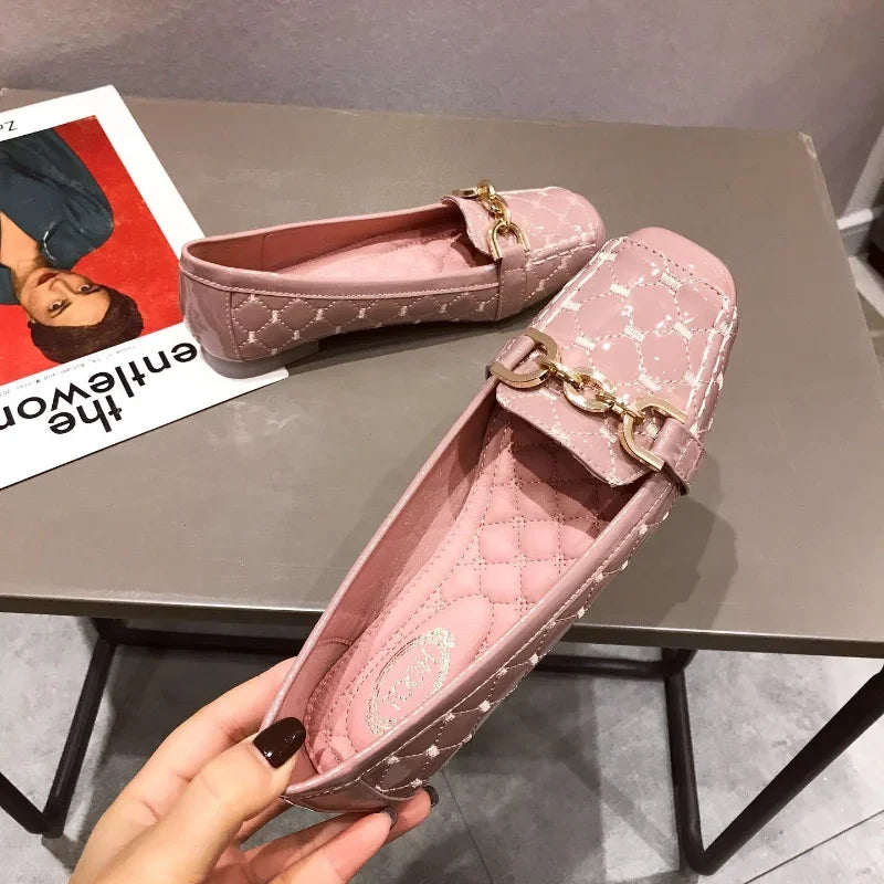 Pink quilted loafers with gold chain detail placed on a gray table beside a magazine featuring a woman's portrait on the cover.