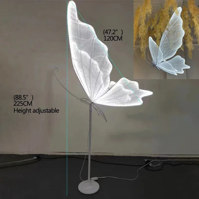 Height-adjustable floor lamp with large, glowing butterfly wings. The wingspan is 120 cm, and the lamp height reaches 225 cm. A smaller version hangs above with yellow decor.