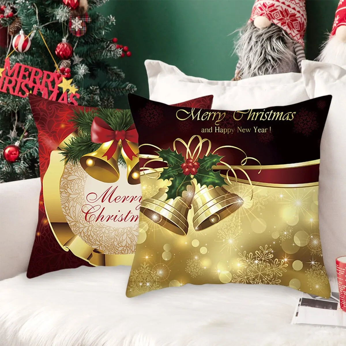Festive Christmas pillows with gold bells and holiday greetings on a white couch, surrounded by a decorated tree with red ornaments and "Merry Christmas" sign.