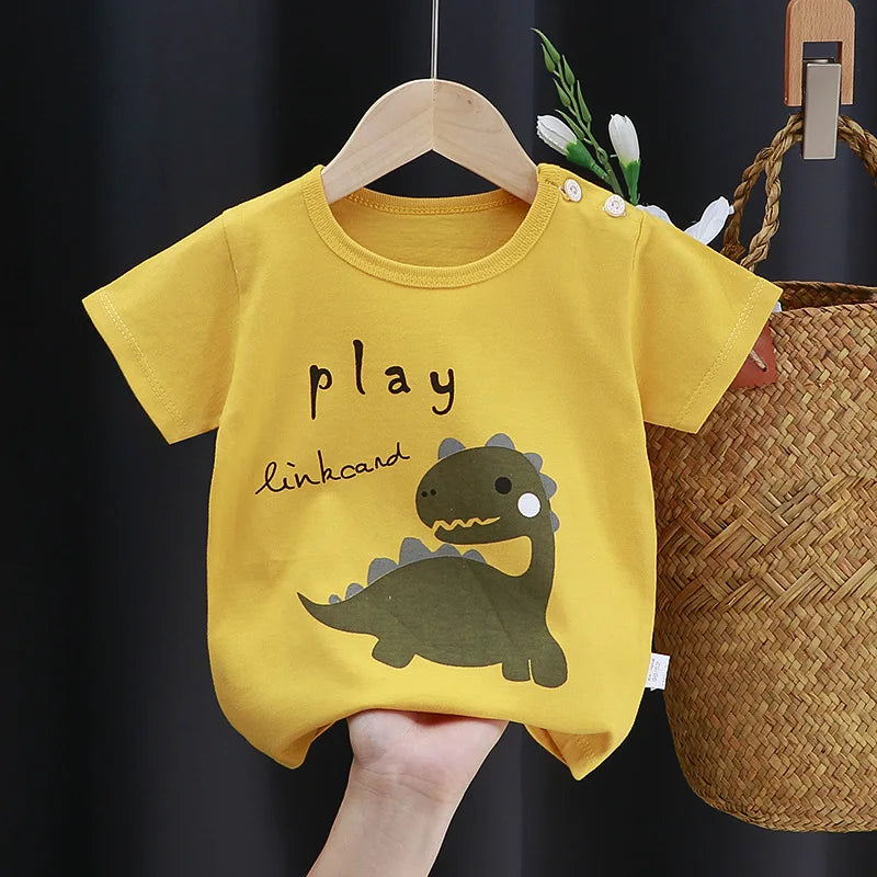 Yellow baby romper with a cute green dinosaur print and the words "play linkcand." It features buttons on the shoulder and is displayed hanging against a dark background.
