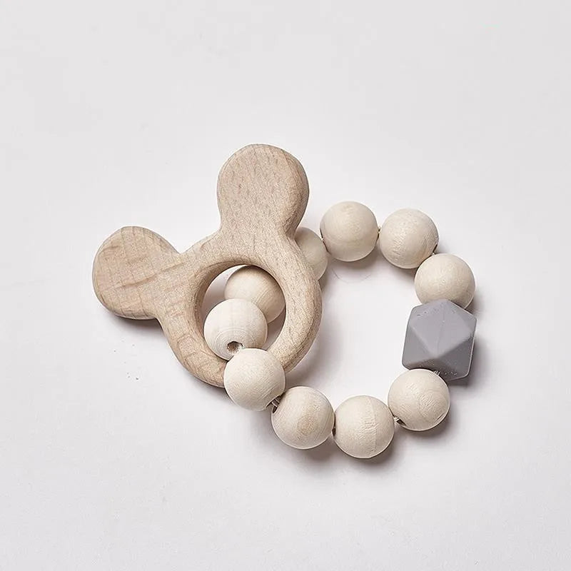 Wooden baby teething ring featuring a bear-shaped handle and a loop of round wooden beads with one gray geometric bead, set against a white background.