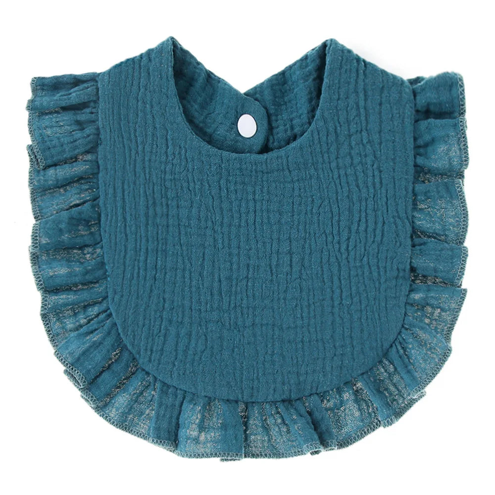 Teal, textured cotton baby bib with a round shape, ruffled edges, and a snap closure at the neck.