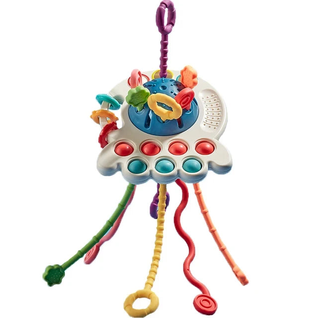 Colorful baby sensory toy featuring a UFO shape with textured, dangling cords and attached shapes, designed for tactile and visual stimulation.