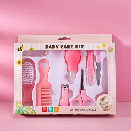 Pink baby care kit with brush, comb, nail clippers, scissors, and more in a decorative box featuring flowers and bees. Labels indicate BPA-free, suitable for 0+ months, and no safety hazard.