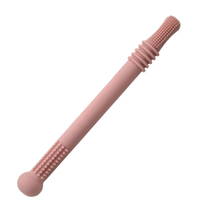 A pink silicone utensil with textured grips on both ends, featuring grooves and small dots, resembles a brush or massage tool.