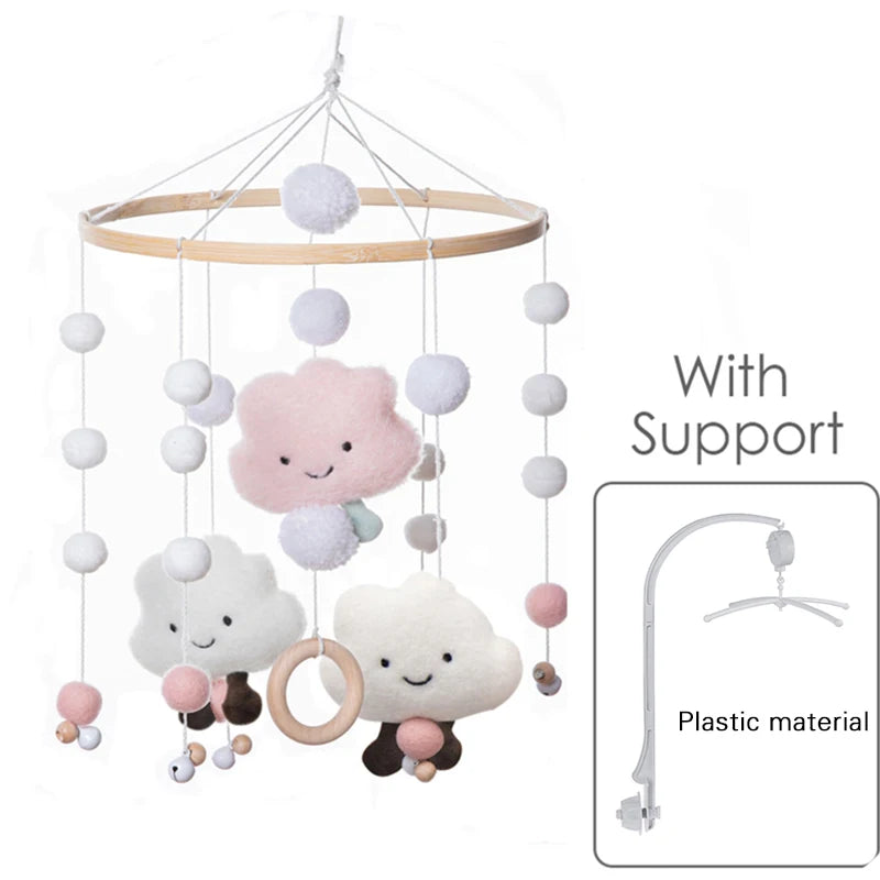 Baby mobile with smiling cloud and ball plushies, hanging from a wooden hoop. Includes pink and white accents, wooden ring, and a plastic support arm for mounting.
