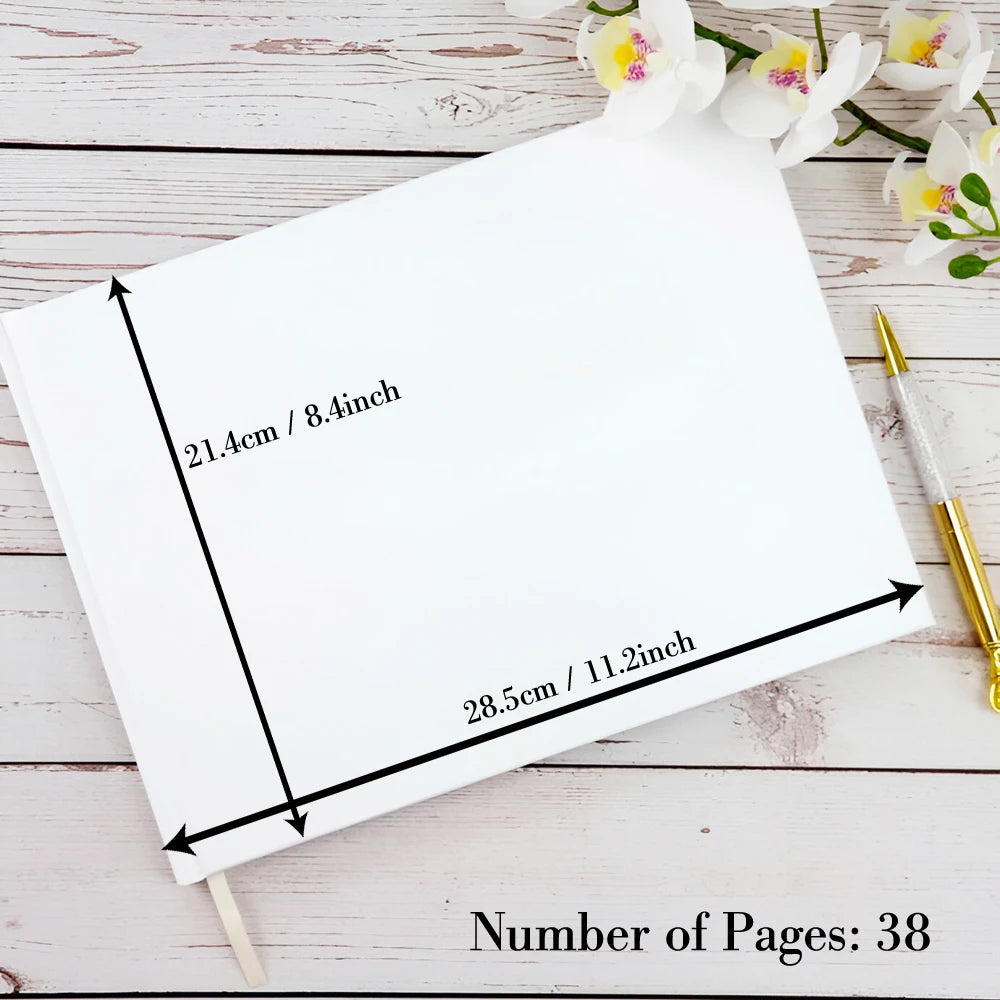 A blank white notebook on a wooden table with measurements, 21.4cm by 28.5cm, and a gold pen beside it. Text indicates the notebook has 38 pages. White flowers are partly visible.