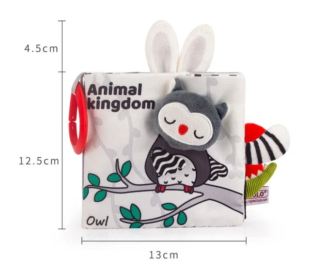 Soft baby book titled "Animal Kingdom" featuring an owl design. The book measures 13cm by 12.5cm. Includes plush texture, bunny ears, and a red ring attachment.