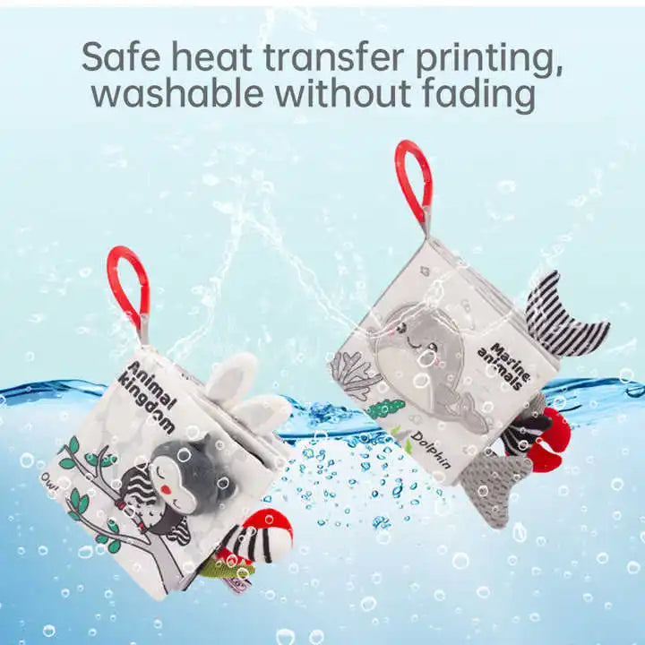 Two fabric children's books with animal illustrations and red handles are submerged in water. Text above reads: "Safe heat transfer printing, washable without fading."