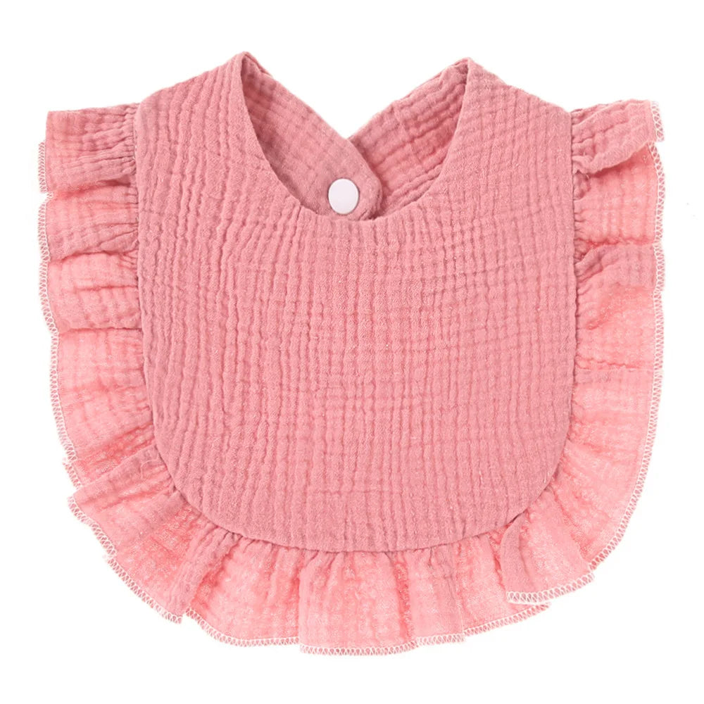 Pink bib with ruffled edges and a textured fabric, featuring a snap closure at the neck.