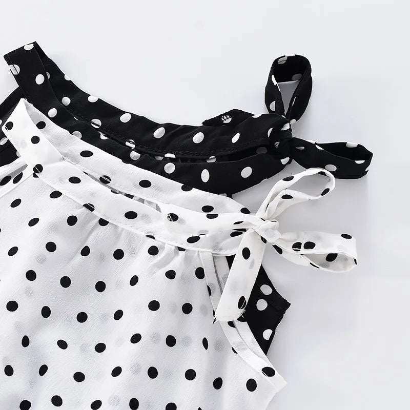 Black and white polka dot dress with contrasting patterns, featuring a bow on the shoulder and a tied waist, displayed on a light background.