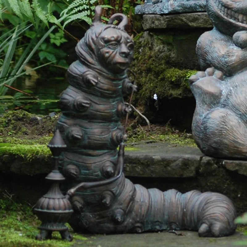 A whimsical garden statue of a caterpillar with a human-like face, holding a hookah, set on a mossy stone surface surrounded by lush greenery.