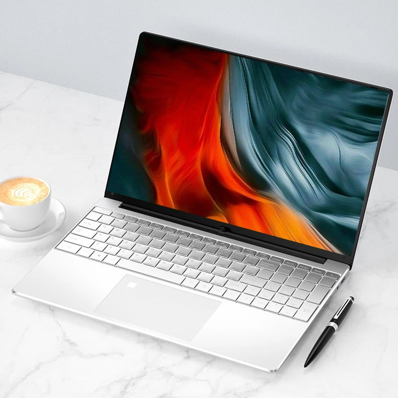 Sleek silver laptop on a marble surface displaying abstract red and blue art. A cup of latte with foam art sits to the left, and a black pen lies on the right.