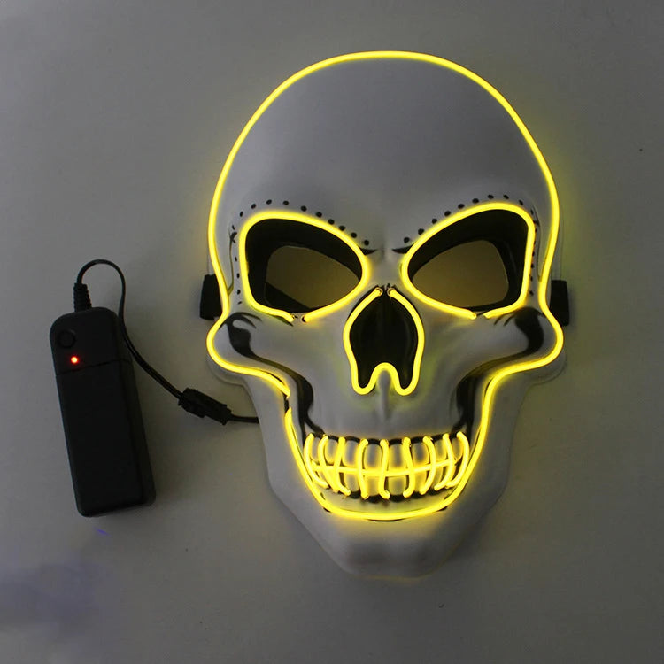 A white skull mask outlined with glowing yellow neon lights, featuring black eye sockets and nose. An attached black battery pack powers the illumination.