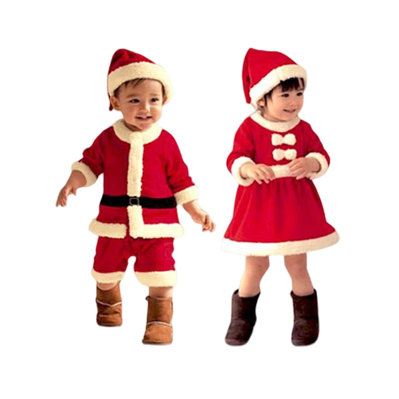 Two toddlers dressed in festive Santa outfits; the boy in a red suit with a hat, the girl in a red dress and hat. Both wear brown boots and smile against a white background.