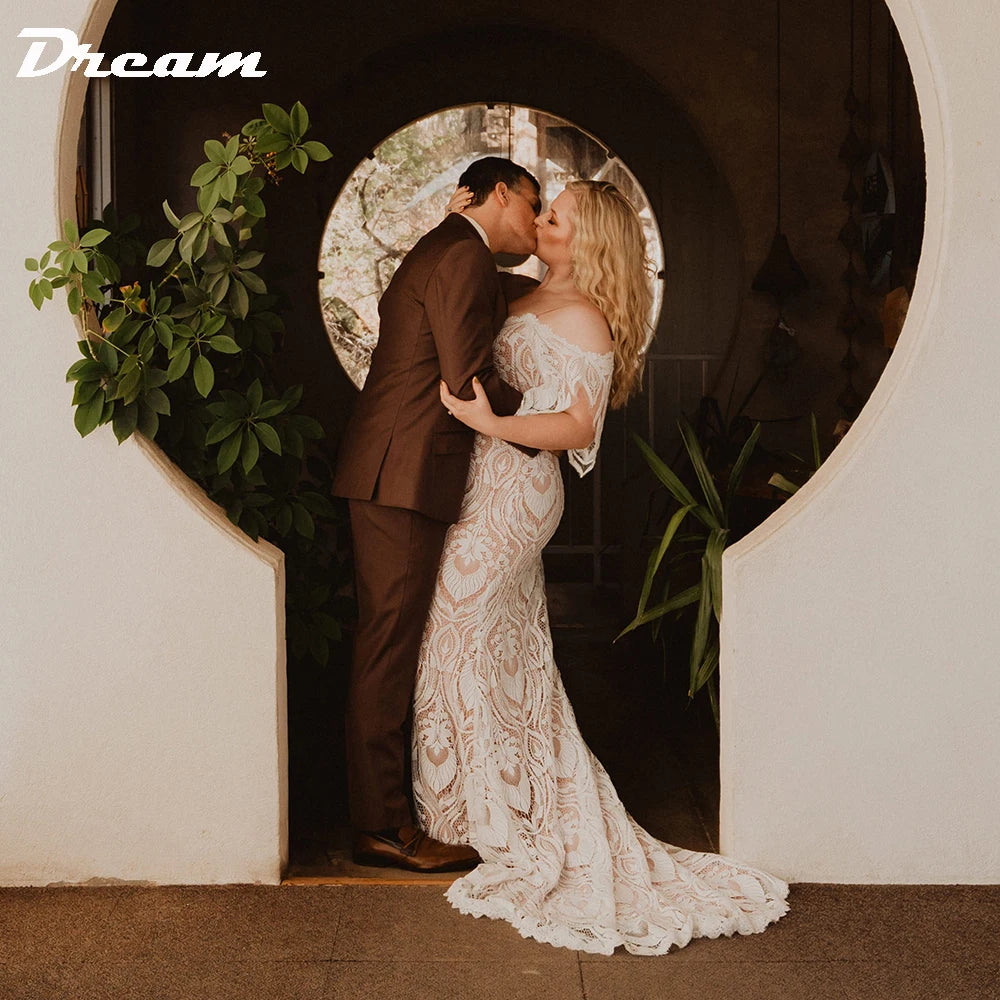 A couple kisses in a circular doorway, surrounded by plants. The woman wears a lace wedding dress, and the man wears a brown suit. The word "Dream" is in the top left corner.