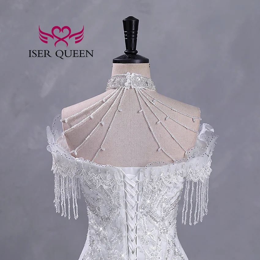Back view of an ornate white wedding dress with intricate lace-up detailing, pearl and bead embellishments, and an elegant beaded choker on a mannequin. Logo reads "Iser Queen."