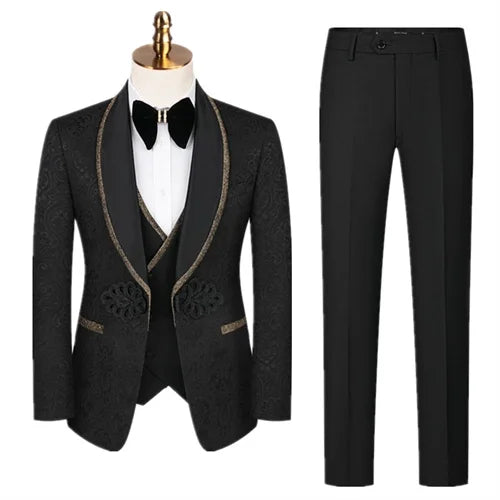 Men's black tuxedo displayed on a mannequin, featuring a satin shawl lapel and intricate floral patterns. Paired with matching black trousers, a white shirt, and a black bow tie.