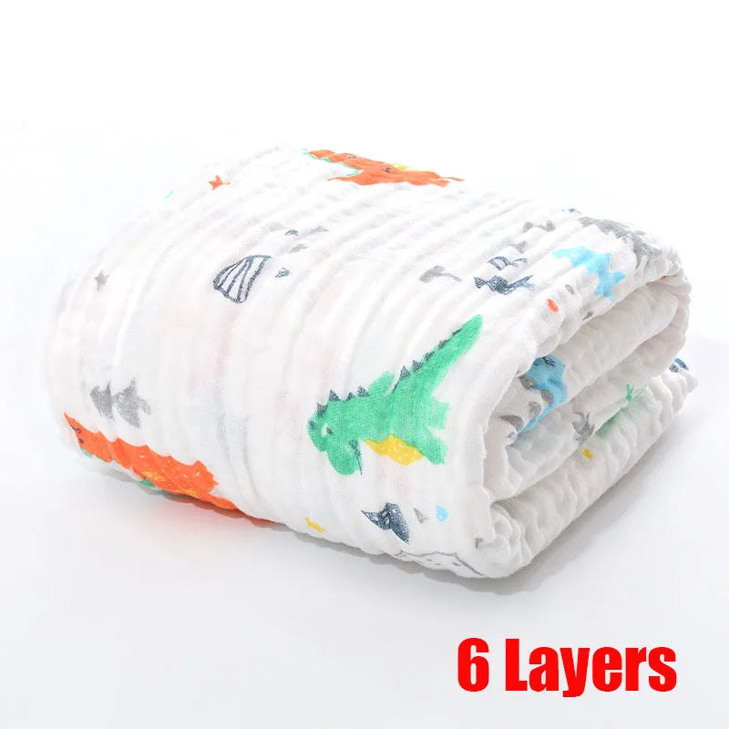 Folded white muslin cloth with colorful dinosaur prints, featuring six layers. The text "6 Layers" is in bold red at the lower right corner.