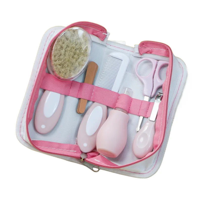 Pink baby grooming kit with a brush, comb, nail scissors, dropper, emery board, and clippers organized in a pink and white zippered case.