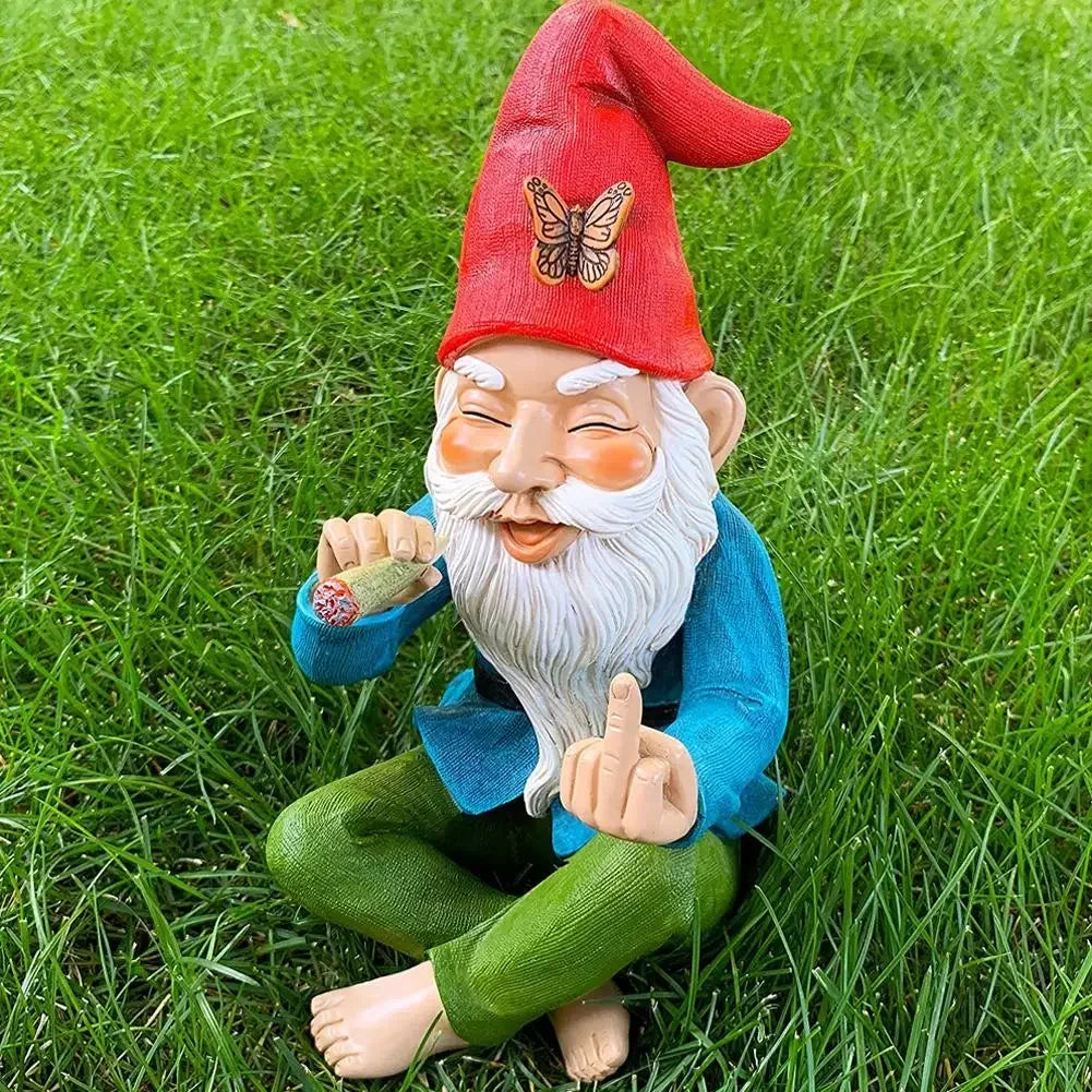 A garden gnome with a red hat and butterfly detail sits cross-legged on grass, holding a joint and making a cheeky gesture with his hand, wearing a blue shirt and green pants.