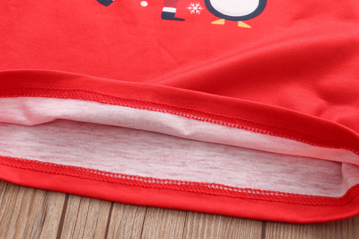 Close-up of the hem of a red fabric garment with a visible white lining and neat red stitching, laid flat on a wooden surface.