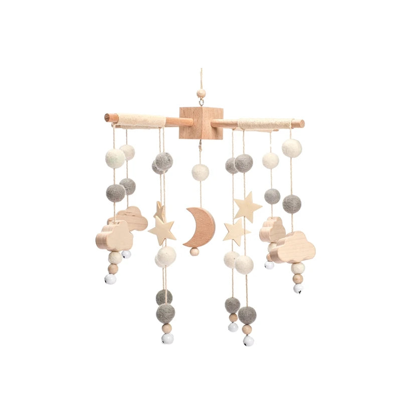 Wooden baby mobile with felt balls, stars, clouds, and a crescent moon, suspended from a crossbar. The natural colors are beige, white, and gray, creating a soothing look.