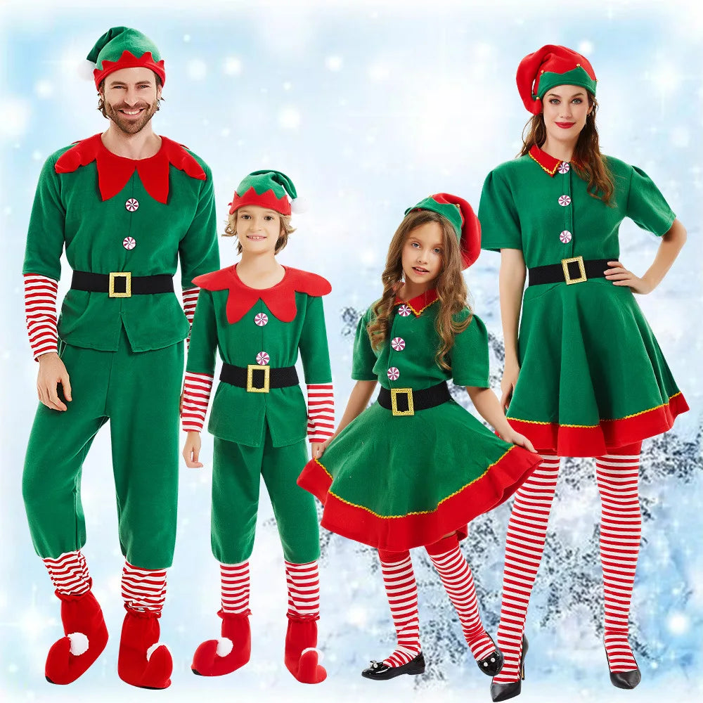 A family of four dressed in matching green and red elf costumes with striped socks and elf hats, standing against a snowy, festive background.