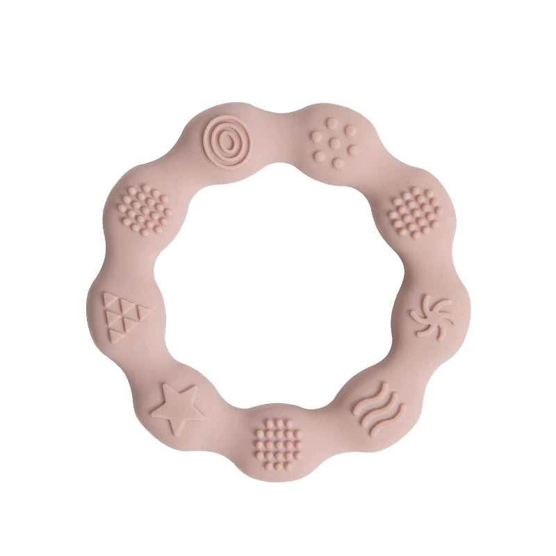 A pink silicone teething ring with a wavy edge, featuring various textured patterns like stars, circles, and waves, designed to soothe a baby's gums.