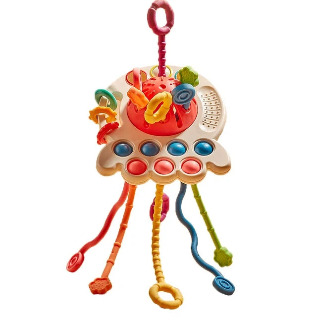 Colorful baby sensory toy with vibrant rings and textured strings hanging from a round base featuring blue and pink buttons, encouraging tactile and visual engagement.