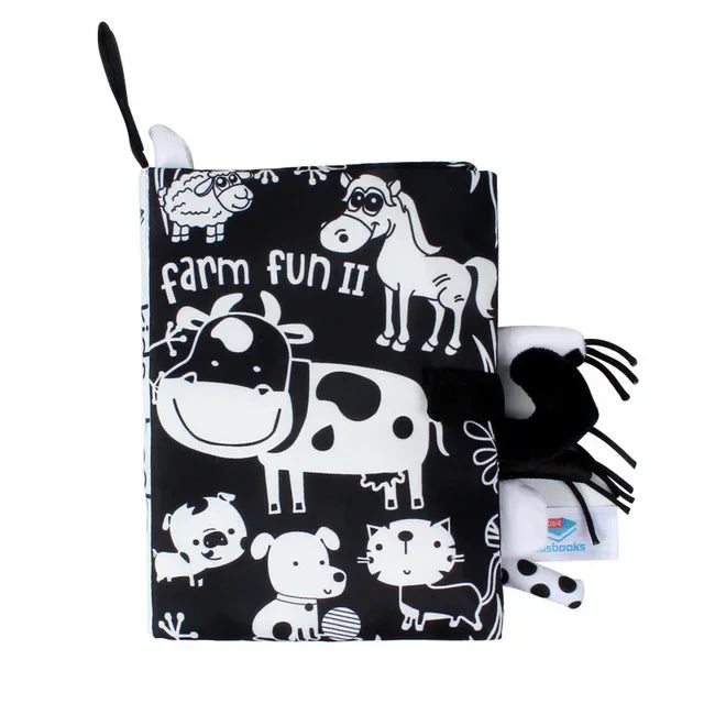 Black and white soft book titled "Farm Fun II" featuring cartoon farm animals like a cow, horse, sheep, dog, cat, and pig. Book is closed with visible black Velcro strap.